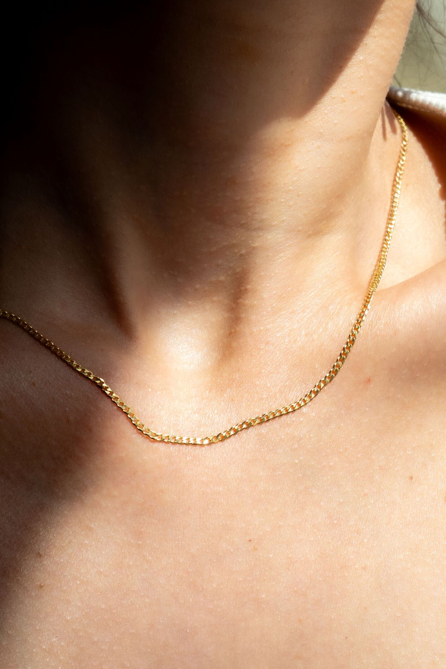 Yellow gold curb chain worn on a woman's neck